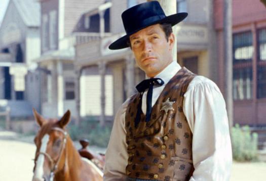 Hugh O'Brian, US actor, in costume leaning against a post, with a horse in the background, in a publicity portrait issued for the US television series, 'The Life and Legend of Wyatt Earp', USA, circa 1958. The western series starred O'Brian as 'Marshall Wyatt Earp'. (Photo by Silver Screen Collection/Getty Images)